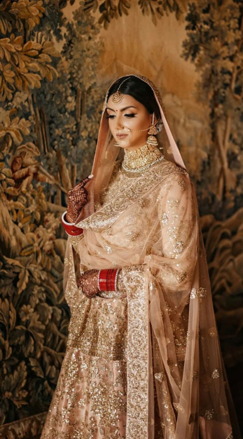 Pastel Punjabi bridal lehenga and traditional jewelry, perfect for wedding photos"
