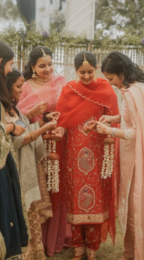 Candid moment of a Punjabi bride laughing with bridesmaids during wedding preparations
