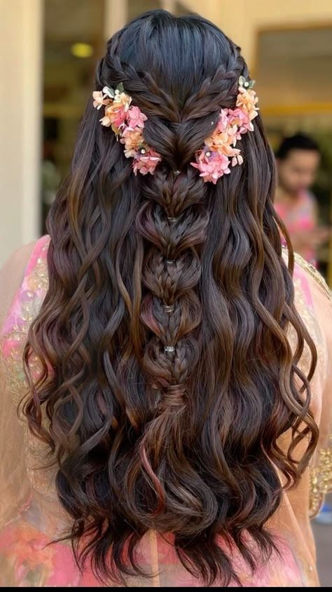 Romantic braided half-up hairstyle with cascading waves, adorned with soft pink floral accents — ideal for Jaago or Mehendi ceremonies.
