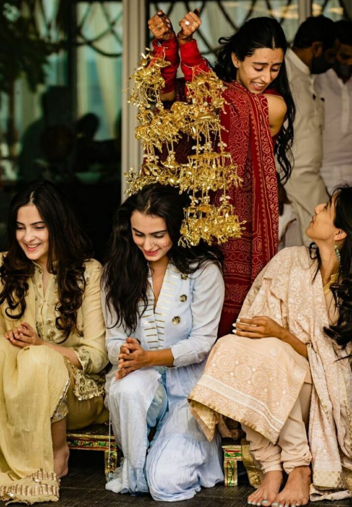 Punjabi bride shaking kaleeras over bridesmaids during traditional wedding ceremony