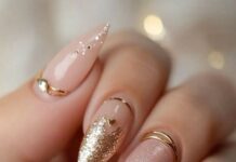 Punjabi Bridal Nail Designs That Will Trend in 2025 Nude and gold Punjabi bridal nail design with heart accents, glitter tips, pearls, and gold rings — trending 2025 nail art for brides