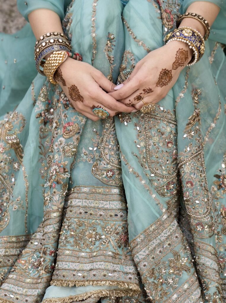 Close up of dusty blue bridal lehenga with jewellery and mehendi detailing
